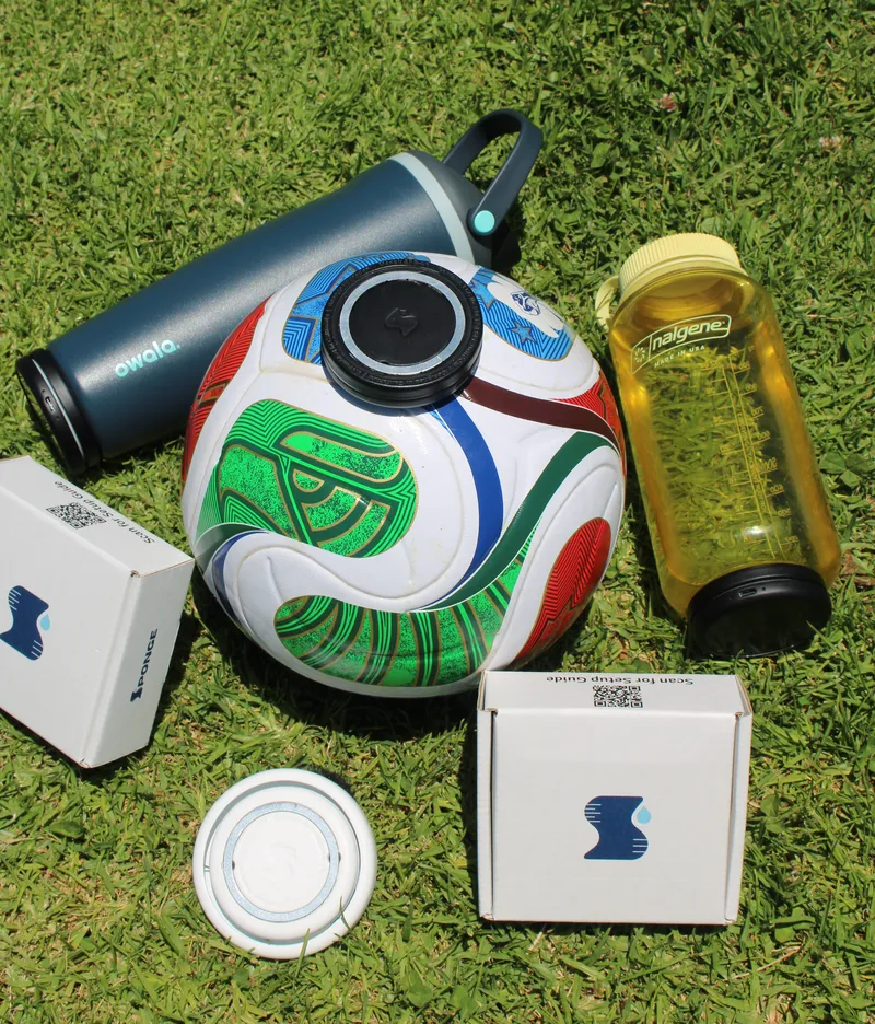 Sponge trackers clipped onto an Owala and a Nalgene water bottle on the grass, next to Sponge packaging.