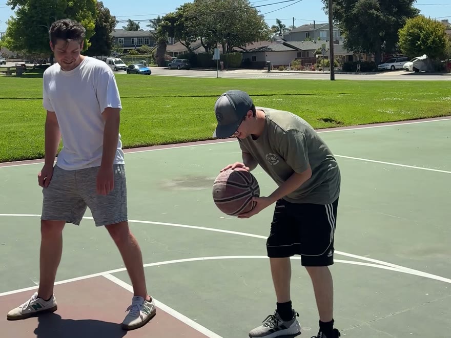 Two friends playing basketball at an outdoor court